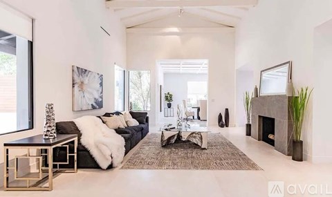 A modern living room with a black couch and a fireplace.