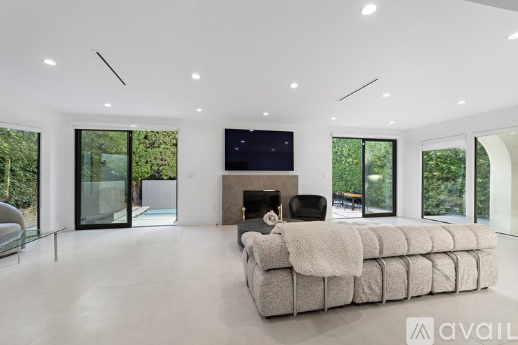A bedroom with a large bed and a window overlooking greenery.