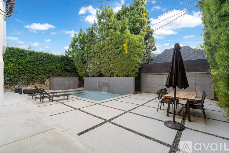A patio with a table and chairs overlooking a pool.