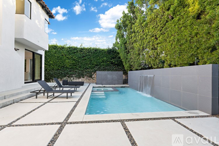 A modern house with a pool and lounge chairs.