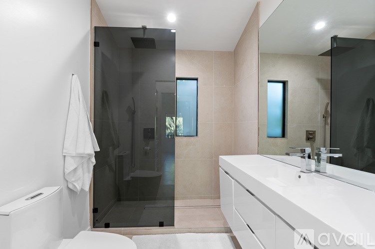 A white bathroom sink with a glass shower door.