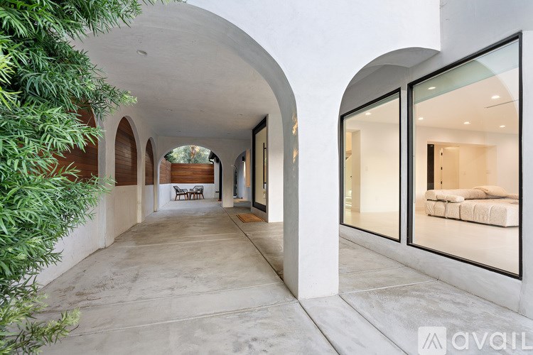 A long hallway with arched doorways and a bench in the distance.