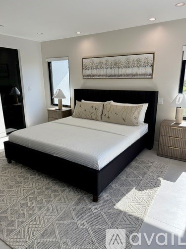 A modern living room with a black sofa and a large painting on the wall.