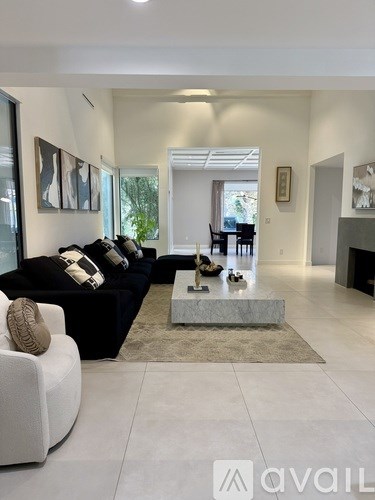 A glass dining table with four chairs and a vase with flowers on it.