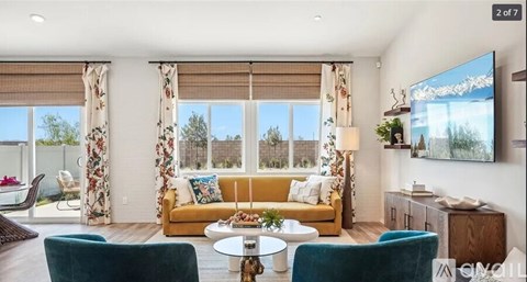A living room with a yellow couch and a flat screen TV mounted on the wall.