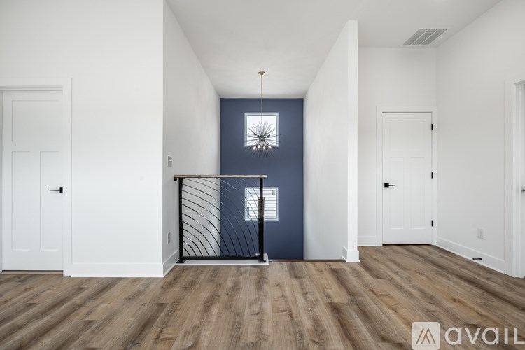 A room with a white door, a window with a white frame, and a wooden floor.
