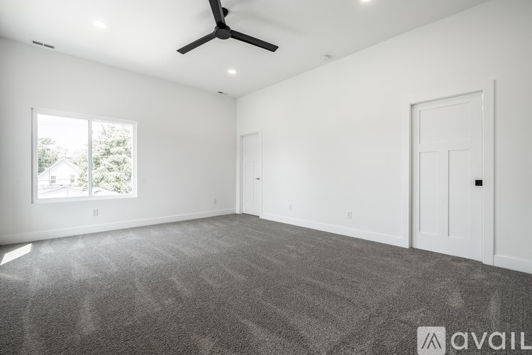 A spacious room with a ceiling fan and carpeted floor.