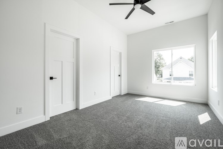 A spacious room with a ceiling fan and a window showing a house outside.