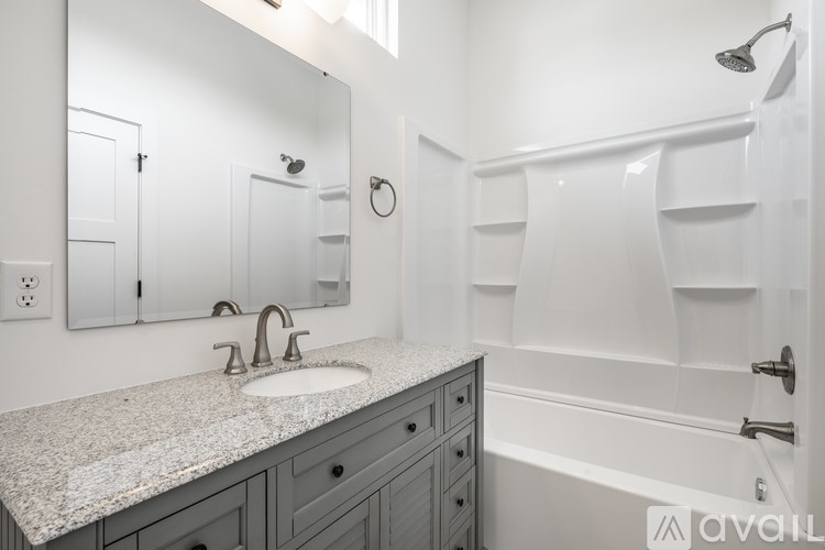 A bathroom with a granite countertop and a white bathtub.