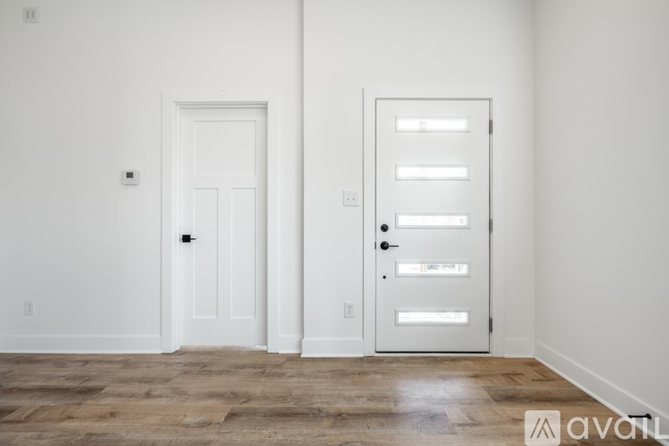 A room with two doors, one with a black handle and the other with a silver handle.