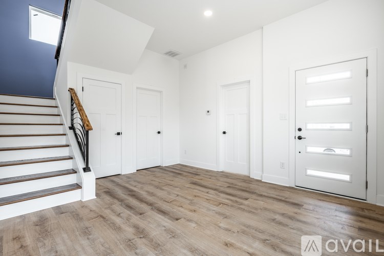 A spacious room with white walls and a wooden staircase.
