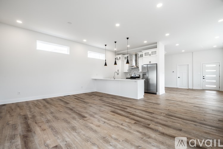 A spacious kitchen with wooden flooring and white walls.