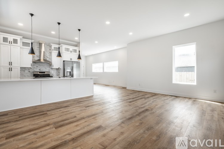 A spacious kitchen with wooden floors and white cabinetry.