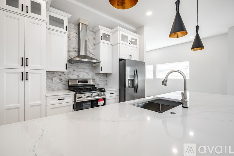 A modern kitchen with white cabinets and a marble backsplash.