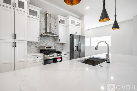 A modern kitchen with white cabinets and a marble backsplash.