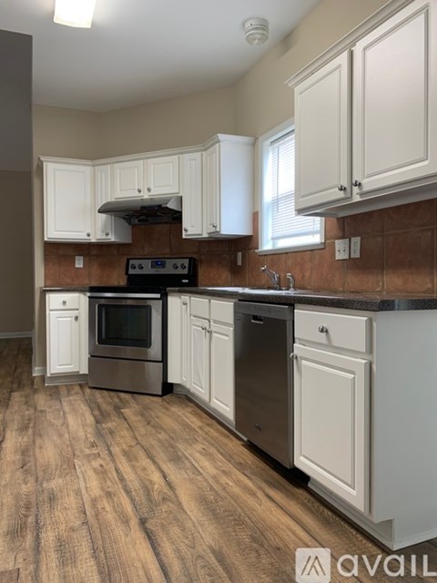 A kitchen with white cabinets and a wooden floor.