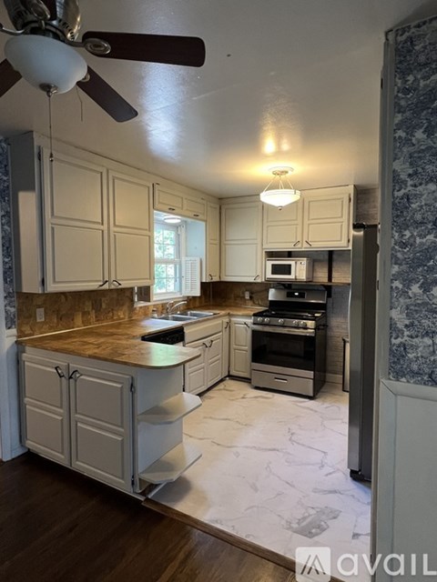 A kitchen with a wooden counter top and white cabinets.