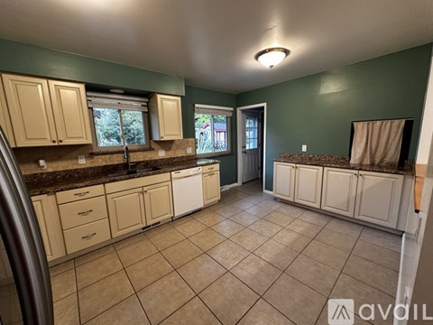 A kitchen with white cabinets and brown countertops.