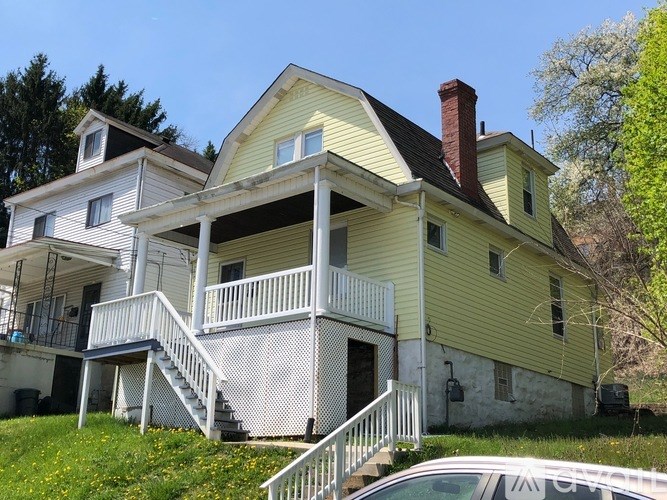 A yellow house with a white car parked in front.