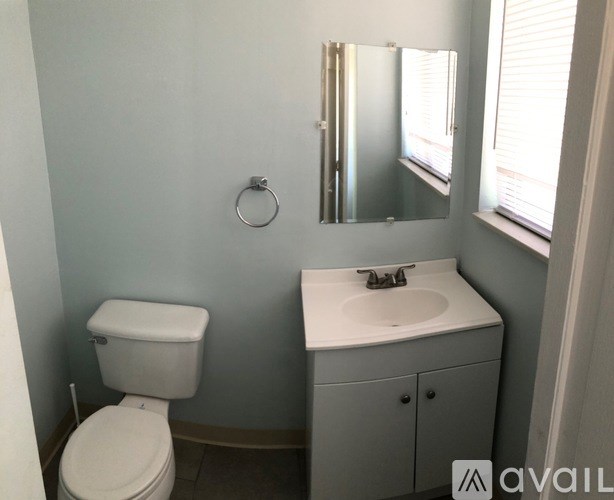 A bathroom with a toilet, sink, and mirror.