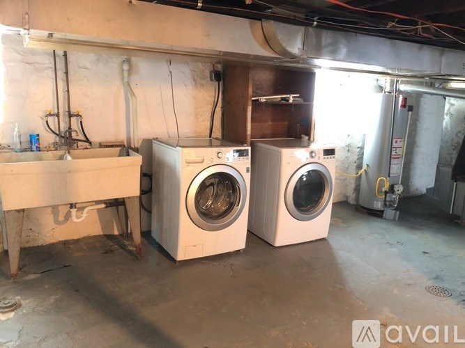Two washing machines are in a dirty basement.