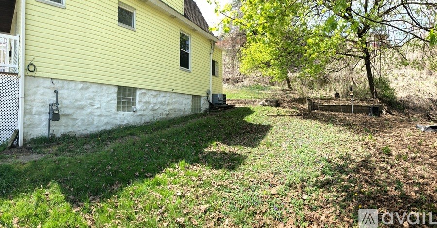 A yellow house with a white fence and a tree in front.