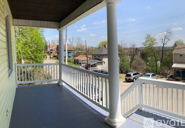 A porch with a white railing and a view of the street.