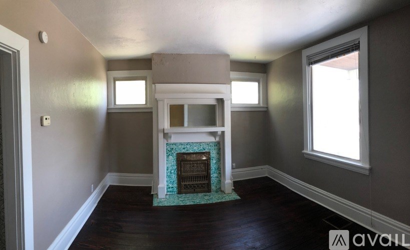 A room with a fireplace and two windows.