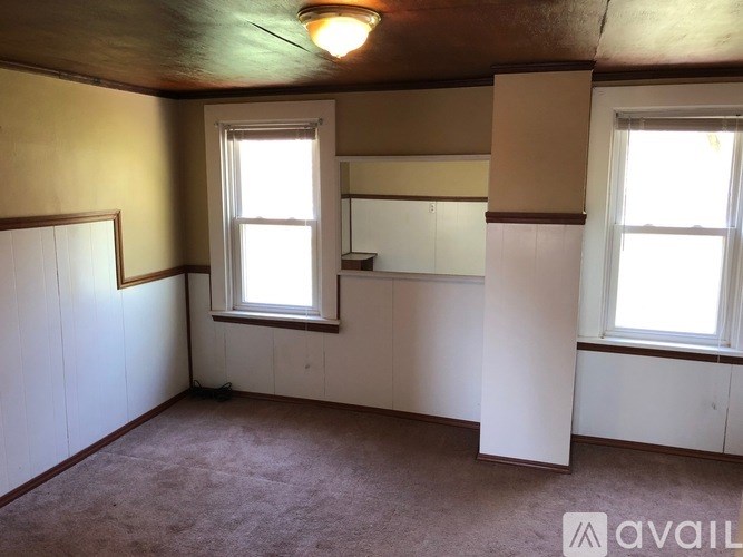 A room with a window and a carpeted floor.