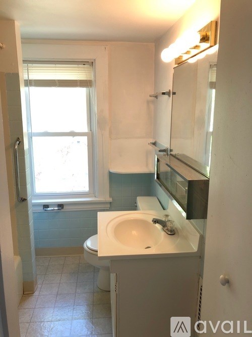 A bathroom with a toilet, sink, and mirror.