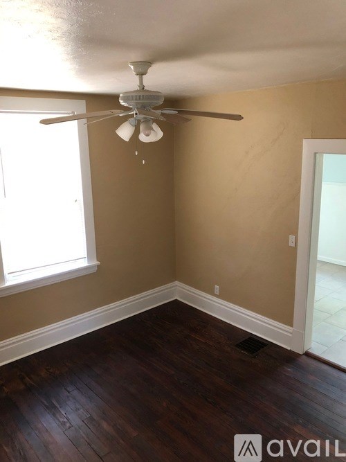 A room with a ceiling fan and wooden flooring.