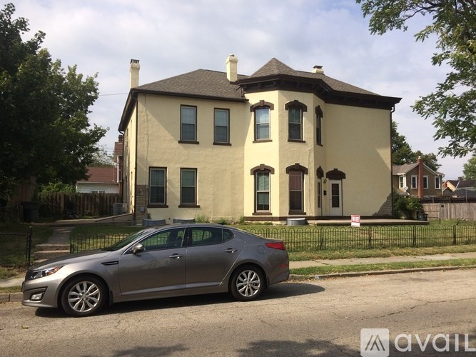 A silver car is parked in front of a two-story house.