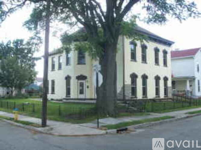 A white two-story building with black railings and a black tree in front.