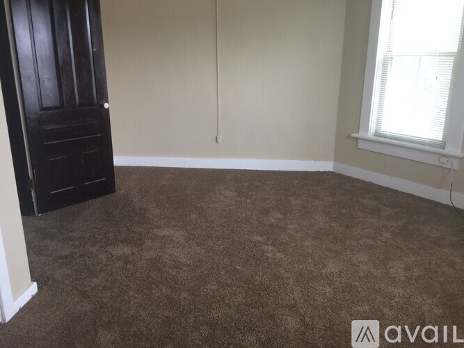 A room with brown carpet and a dark wooden door.