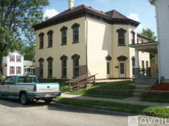 A white truck is parked in front of a tan building.