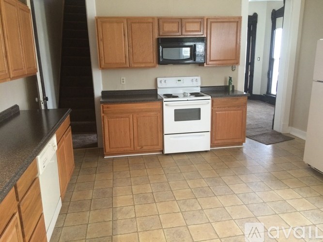 A kitchen with a white stove top oven and black countertops.