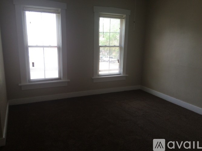 A room with two windows and carpeted floor.