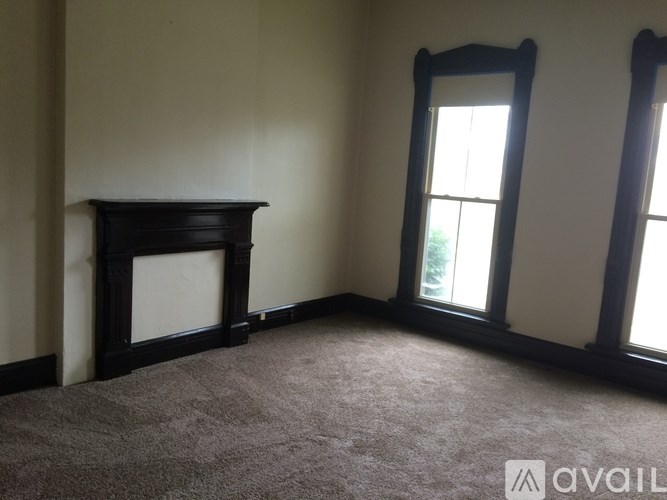 A room with a fireplace and two windows.