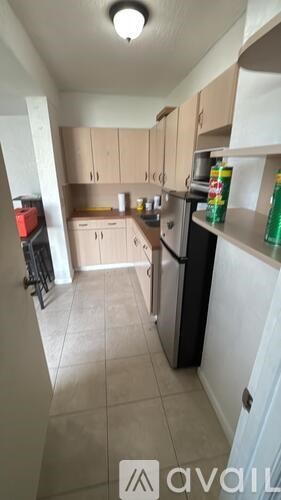A kitchen with a black fridge and white shelves.