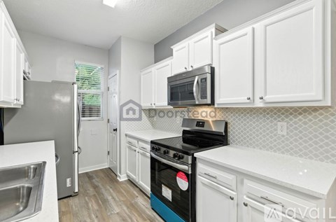 A kitchen with white cabinets and a black stove top oven.