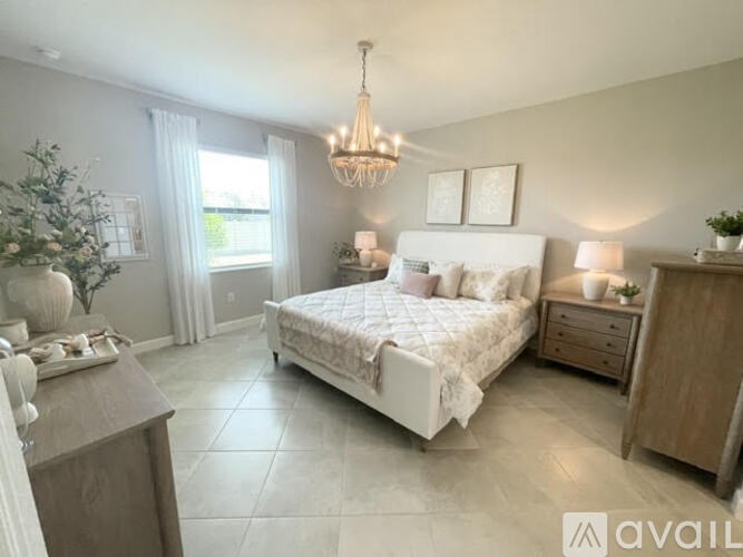 A bedroom with a large bed, a chandelier, and a wooden cabinet.