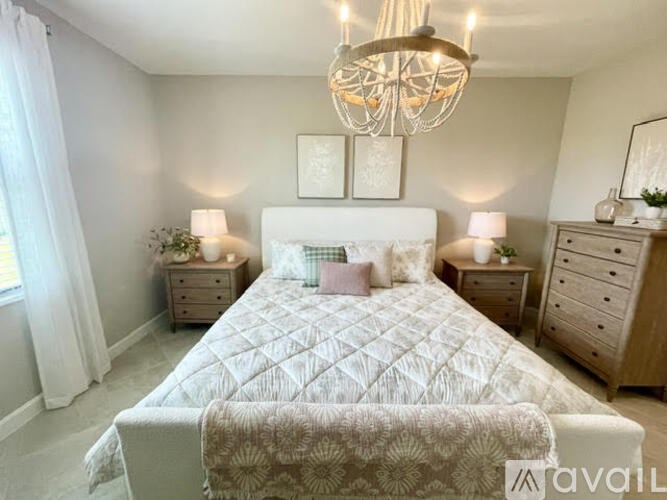 A bedroom with a large bed, two nightstands, and a chandelier.