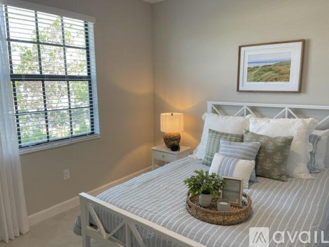 A bedroom with a bed, a lamp, and a picture on the wall.
