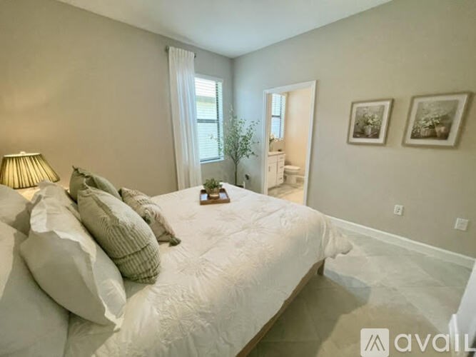 A bedroom with a large bed and two pictures on the wall.