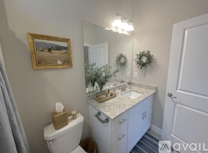 A bathroom with a toilet, sink, and a mirror.