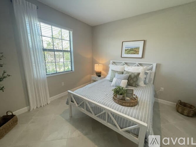 A bedroom with a white bed and a window with curtains.