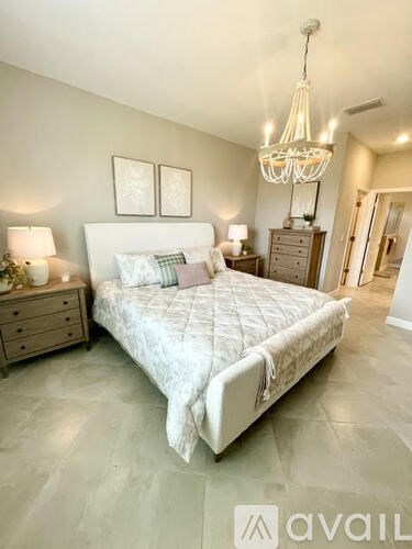 A bedroom with a large bed, a chandelier, and two nightstands.