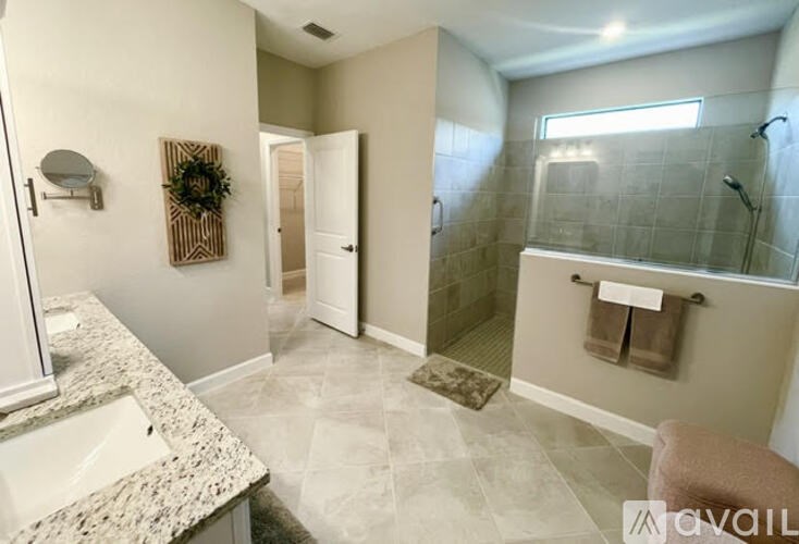 A bathroom with a marble countertop and a glass shower stall.