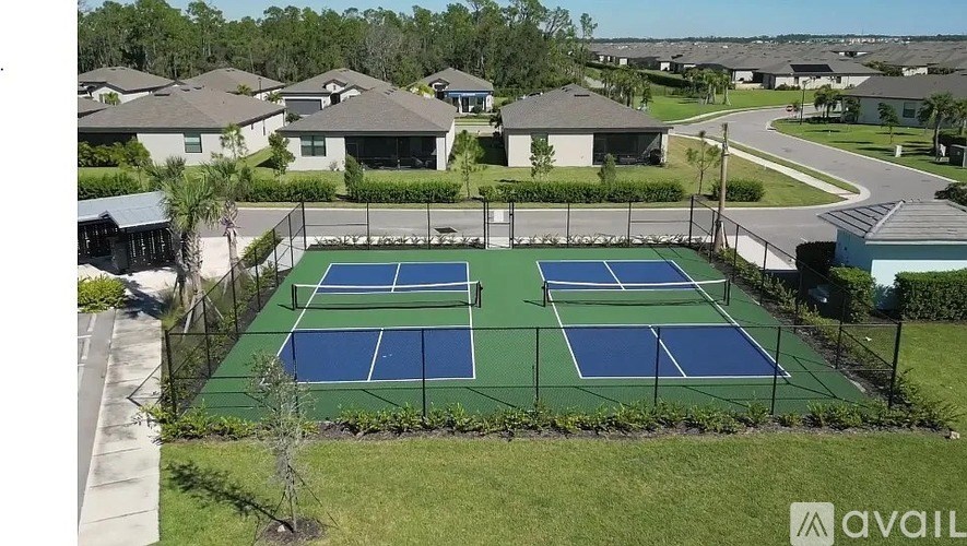 A tennis court surrounded by a fence and houses.