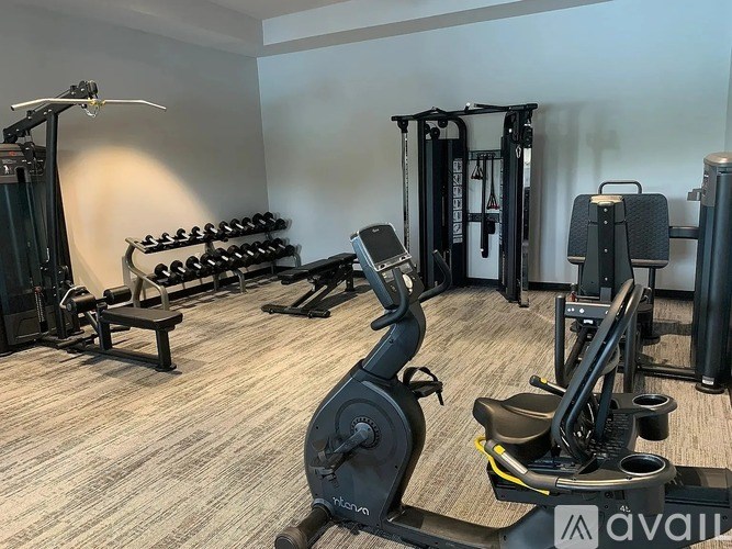 A gym with a variety of equipment including a treadmill, weights, and a bench.